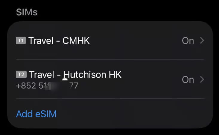 Esta es una captura de pantalla de la pantalla de Ajustes de iPhone que muestra la sección de SIMs, con dos entradas eSIM activadas: Travel - CMHK etiquetada como T1, y Travel - Hutchison HK etiquetada como T2, esta última muestra un número de teléfono de Hong Kong parcialmente difuminado que comienza con +852 51 y termina en 77. Un enlace azul Add eSIM se encuentra debajo de las dos entradas, indicando que el teléfono es dual‑SIM con dos eSIMs de operadores de Hong Kong activas, probablemente configuradas para viajar.